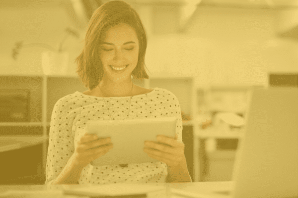 a woman in an office looks at her tablet while smiling